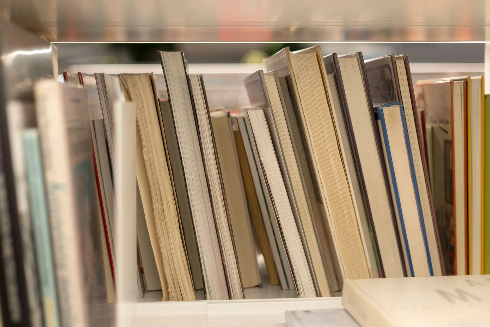 A shelf of books seen edge-on, page blocks and gaps visible but not a single spine title legible.