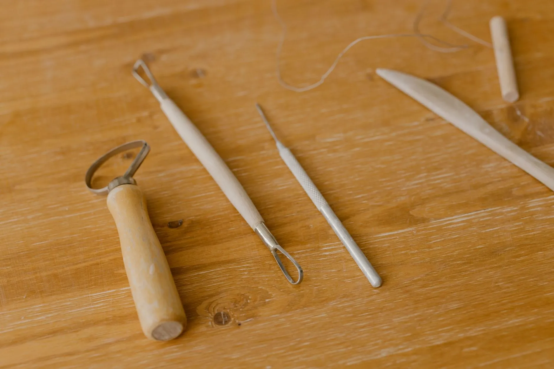 Five specialised modelling tools laid out on a wooden bench, each with a differently shaped tip.