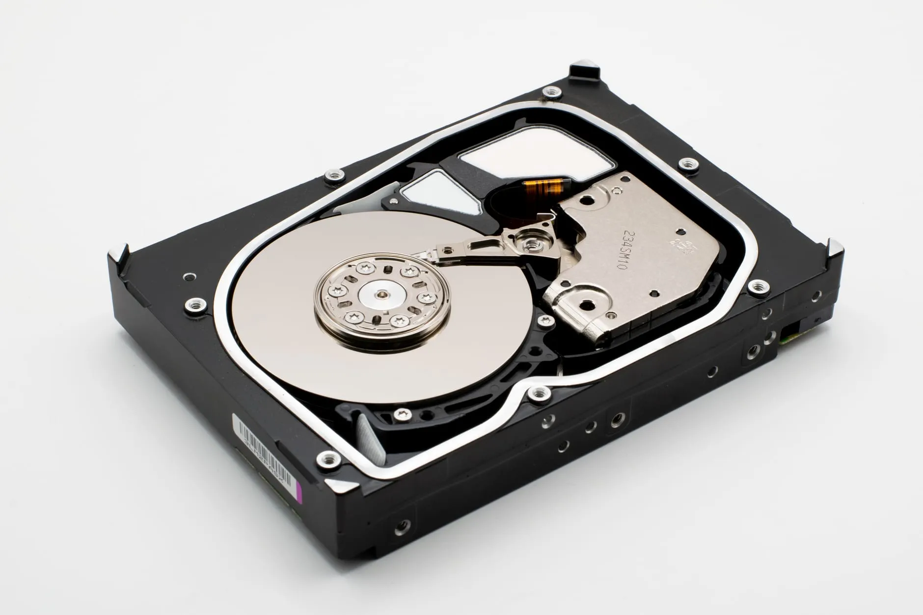 A 3.5-inch hard disk with its lid removed, showing a single mirrored platter, the spindle and the actuator arm resting over it.