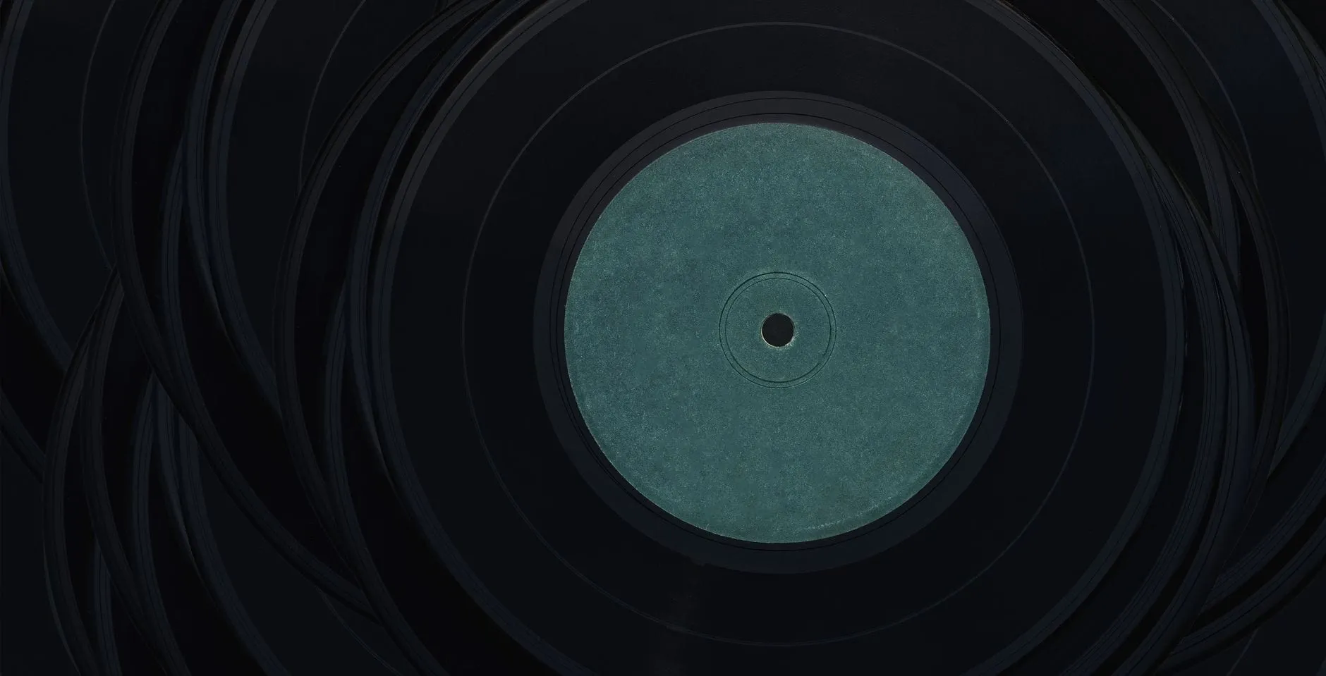 A vinyl record shot from directly above, its centre label a blank disc of teal paper with nothing printed on it.