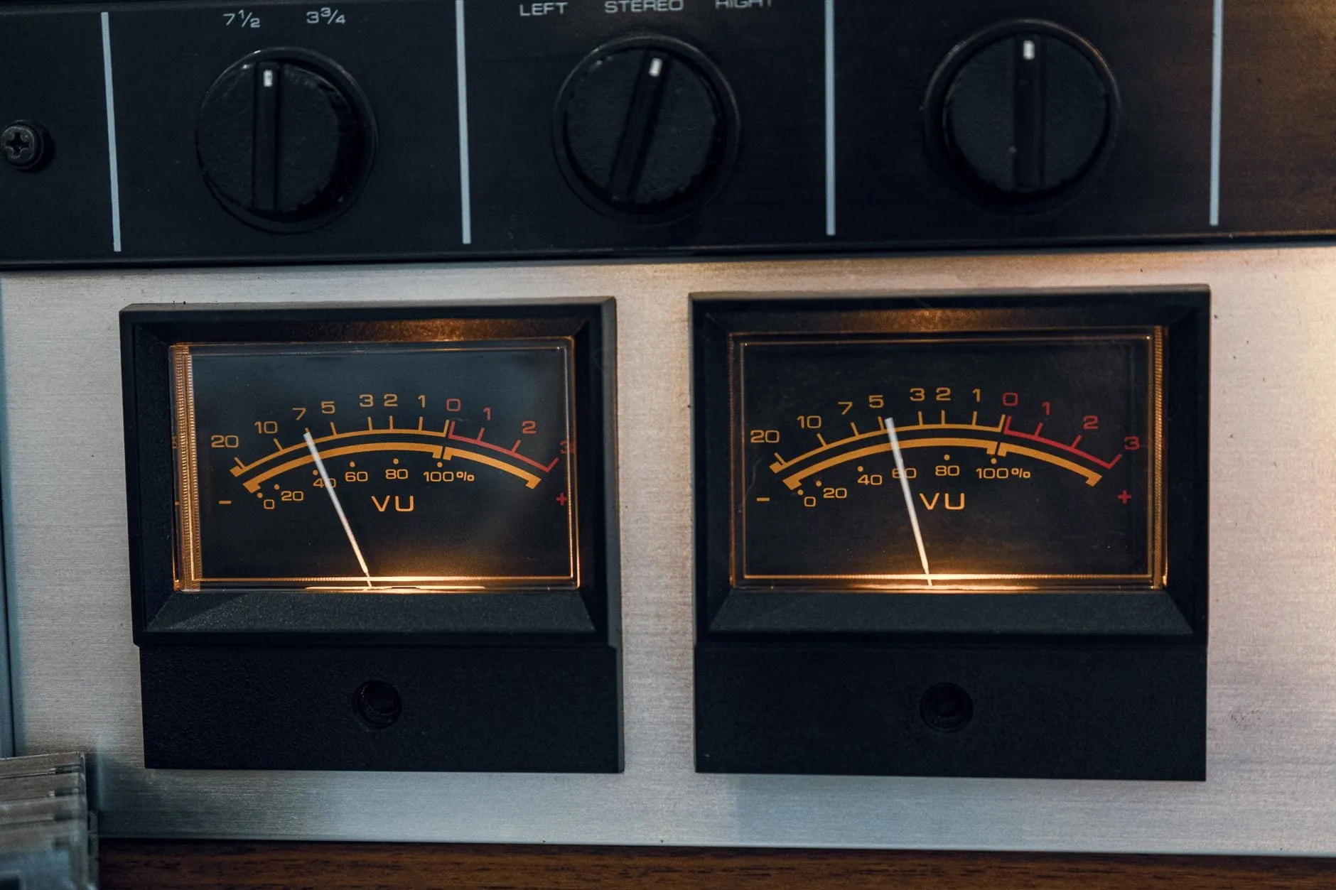 Two illuminated VU meters side by side, both needles resting below zero on scales that turn red past the zero mark.